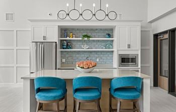 A kitchen with a large island with blue chairs